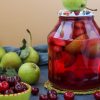 Compote of pears and cherries in jar on table, harvest for the winter, horizontal photo, close-up